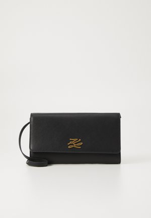 Svart skinnkortholder med en fold-over design, som har en gulllogo og en avtakbar skulderrem. Glatt tekstur, minimalistisk stil.