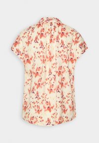 Blusa floreale in tessuto morbido e leggero con base crema e motivi arancioni/viola. Presenta maniche corte e scollo rotondo.
