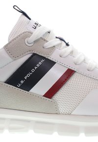 Białe sneakersy z szarymi panelami z zamszu i siateczki. Posiadają niebieskie, czarne i czerwone paski, okrągłe sznurowadła oraz teksturowaną gumową podeszwę.