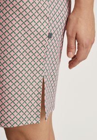 Gonna con motivo geometrico nei colori rosa e verde, con uno spacco laterale, realizzata in tessuto testurizzato. Cuciture visibili e etichetta del marchio sul lato.