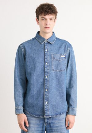 Denim overhemd met knopen, lichtblauw, met een borstzak en een merklabel. Beschikt over een klassieke kraag en lange mouwen met knoopmanchetten.
