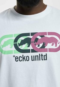 Tricou alb din bumbac, cu un grafic multicolor al rinocerilor în cercuri de culoare verde, neagră și roz, având textul "*ecko unltd."