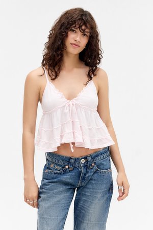 Roze cropped top met verstelbare bandjes, voorzien van een gestrikt voorpand en gerimpelde lagen. Gecombineerd met high-waisted blauwe denim jeans.