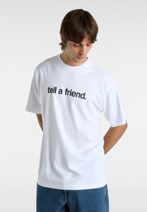 White cotton T-shirt featuring short sleeves and a crew neck. Black text "tell a friend." prominently displayed on the front.