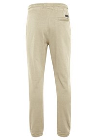 Beige Sweatpants mit elastischem Bund, schmal zulaufenden Beinen und einer einzelnen Gesäßtasche. Weicher Stoff mit einer glatten Textur.