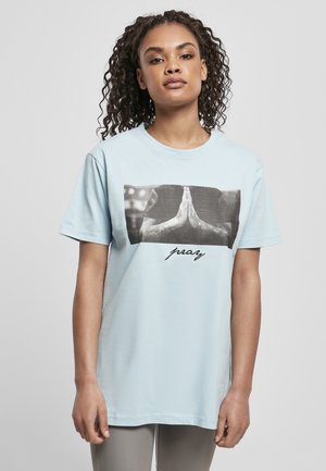 Helles blaues Baumwoll-T-Shirt mit einem Grafikmotiv von Händen in Gebetsposition mit schwarzen Akzenten und dem Wort "pray" in Kursivschrift unter dem Bild.