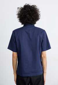Korte mouwen shirt van navy katoen met een zachte textuur en rechte snit. Voorzien van een button-down kraag en een rugpand.