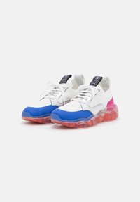Vita sneakers med blå tåhätta och rosa detalj vid hälen. Halvgenomskinlig sula i röd nyans med texturerad yta och snören.