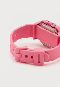 Ροζ ψηφιακό ρολόι χειρός με ρυθμιζόμενο λουρί και μεταλλικό κούμπωμα, απεικονίζεται από την πίσω πλευρά σε λευκή επιφάνεια.