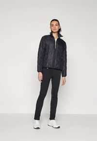 Mustast tikandiga tõmblukuga jope kõrge kaelusega, sobitatud mustade retuuside ja valgete tossudega. Lihtne disain ja sile pind.