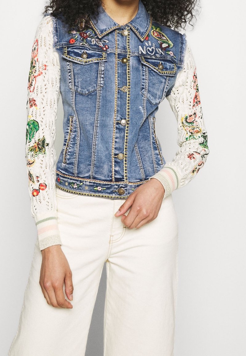Džínová bunda s vyšívanými květinovými vzory na bílých pletených rukávech, se zapínáním na knoflíky, dvěma kapsami a žebrovanými proužkovanými manžetami.