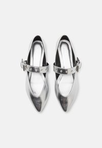 Srebrne metaliczne buty na szpilce z wysmukłym noskiem, z pojedynczym paskiem wokół kostki, z okrągłymi wycięciami i zapięciem na boczną klamrę. Gładka faktura.