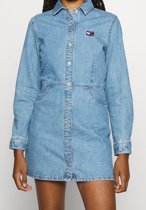 Vaaleansininen nappikiinnitteinen farkkumekko, jossa pitkät hihat ja kaulus. Rinnassa pieni Tommy Jeans -logoplässi.
