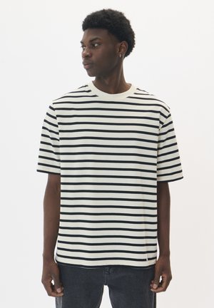 Striped t-shirt with horizontal black and white stripes, short sleeves, crew neckline, loose fit, and a slight curve at the hem.