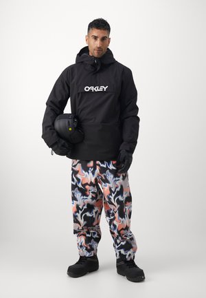 Juodas vandeniui atsparus švarkas su "OAKLEY" logotipu, derinamas su spalvingomis, abstrakčių raštų sniego kelnėmis. Juodos pirštinės ir batai užbaigia aprangą.