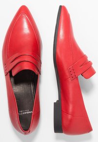 Scarpe in pelle rossa con punta affusolata, caratterizzate da una superficie liscia e da due cinturini sulla parte superiore del piede. Suola in gomma nera.