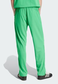 Zelené, ľahké športové nohavice s elastickým pásom, obtiahnutým strihom a bočnými vreckami. Materiál má hladkú, priedušnú textúru.
