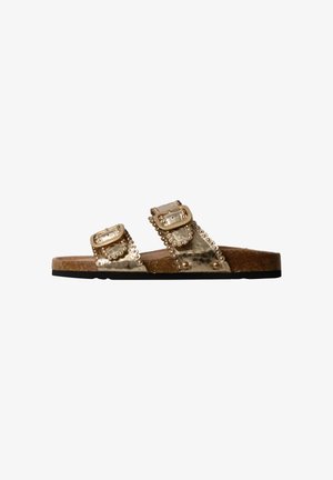 Flat brown sandal with cork sole and two metallic gold straps featuring decorative buckles and small studs.