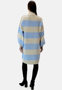 Stickad klänning i sweaterstil med horisontella ljusblå och beige ränder, hög hals, överdimensionerade ärmar och ribbad fåll, når till knäna.