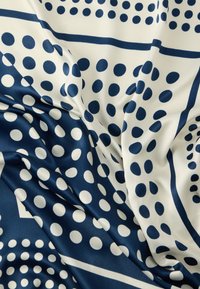 Satīna audums ar baltu fonu, tumši ziliem punktiņiem un ģeometriskām līnijām, veidojot ritmisku rakstu ar gludu tekstūru.