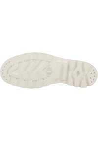 Suola della scarpa in gomma bianco sporco con motivi di trazione testurizzati, caratterizzata da un logo in rilievo e da molteplici scanalature per la stabilità.