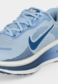 Ανοιχτό μπλε αθλητικό παπούτσι Nike με μπλε λογότυπο Swoosh, υφασμάτινο επάνω μέρος με υφή και επενδυμένη σόλα σχεδιασμένη για άνεση και απόδοση.