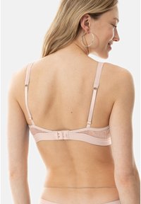 Soutien-gorge rose clair avec des accents en dentelle, des bretelles réglables et une fermeture à crochets dans le dos. Tissu lisse avec une texture douce.