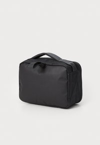 Svart rektangulær bag med teksturert overflate, med to stoffhåndtak og glidelåslukking. Kompakt design som er egnet for oppbevaring.