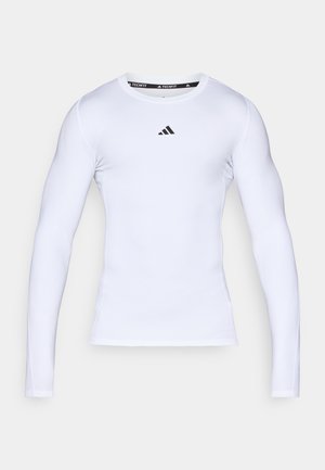 T-shirt de sport à manches longues blanc fabriqué en tissu extensible, avec un col rond et un logo Adidas noir sur la poitrine.