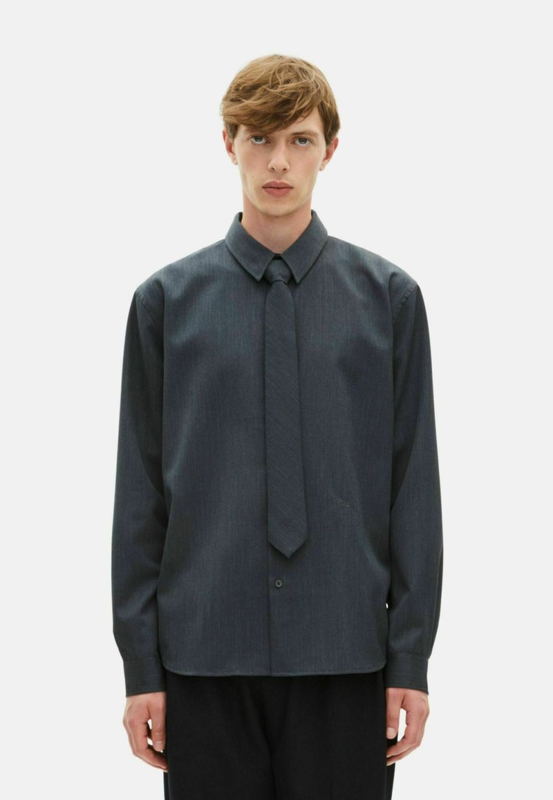 Dunkelgraues Langarmshirt mit einem Knopfkragen, Frontknöpfen und einer passenden Krawatte. Glattes Material mit einer subtilen Textur.