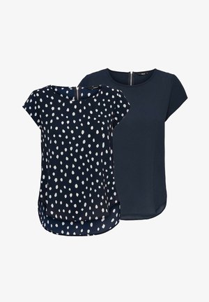 Two women's tops: one navy blue with white polka dots, the other solid navy. Both feature short sleeves and a rounded hem.