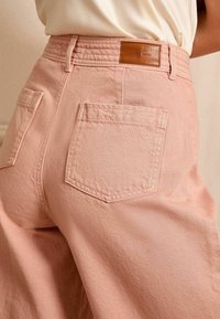 Roze wijd uitlopende broek van textuurstof met een hoge taille, elastische band en achterzakken, met een leren label op de tailleband.