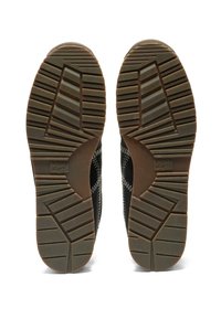 Suela de zapatillas negra con goma texturizada, que presenta un patrón de bandaje para mayor agarre, detalle de logo lateral y un diseño de punta suave y redondeada.