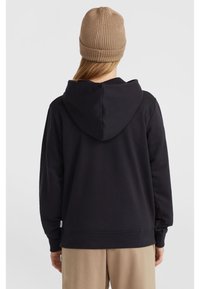 Black hoodie with a drawstring hood, ribbed cuffs, and hem. Worn with a beige knitted beanie, displayed from the back against a light background.