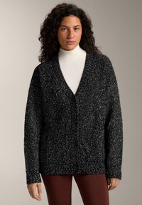 Black and white speckled cardigan with a v-neck, long sleeves, and button front closure, made from a textured knit material.