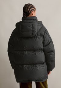 Μαύρο φουσκωτό μπουφάν με κουκούλα, με επενδεδυμένο σχέδιο, εμπρόσθιες πάνελ και ελαστικούς καρπούς. Λείο υλικό με άνετη εφαρμογή.