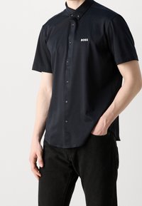Korte mouwen donkermarine blauwe overhemd met knopen en een puntkraag, met een klein wit "BOSS" logo op de linkerborst en een gladde textuur.