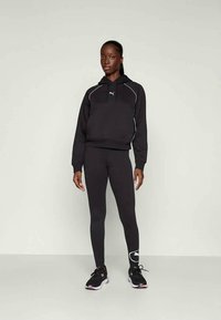 Črna kapuco s puloverjem in belimi detajli, v kombinaciji s črnimi leginsami. Obleko dopolnjujejo črne športne čevlje s roza podrobnostmi.