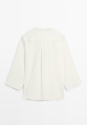 Langærmet hvid skjorte med rygstykke og middelstykke, vist fladt med bagsiden opad på en hvid baggrund.