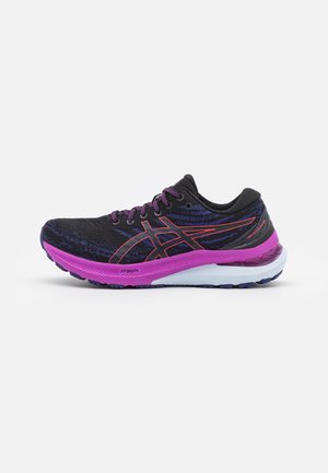 Chaussure de course noire et violette avec des accents rouges sur le logo, semelle intermédiaire violette, semelle extérieure blanche et violette, et lacets noirs sur fond blanc.