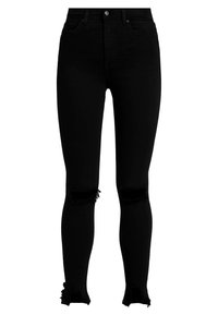 Jeans skinny de denim negro con detalles de rodillas desgastadas y dobladillos deshilachados; presenta una cintura de media altura y un diseño de cinco bolsillos.