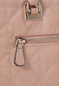 Jasnoróżowa pikowana torebka z wytłoczonymi wzorami, złotymi akcentami i kieszonką zapinaną na zamek z uchwytem. Gładkie, teksturowane wykończenie.