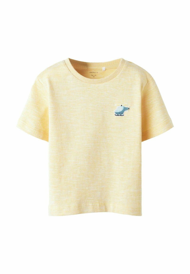 T-shirt de algodón amarillo con cuello redondo y mangas cortas. Presenta un detalle bordado de un helicóptero azul en el lado izquierdo del pecho.