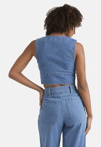 Gekürztes Denim-Oberteil in Hellblau mit ärmellosem Design. Verfügt über einen geraden Saum und sichtbare Nähte entlang des Halsausschnitts und der Armausschnitte.