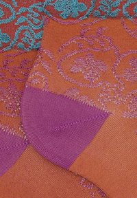 Calze testurizzate in corallo con motivo floreale teal, tallone e punta viola, caratterizzate da una trama simile a una rete e accenti a contrasto.