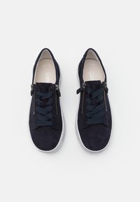 Dark navy suede sneakers with a textured upper, featuring navy laces and side zippers, and a white rubber sole.