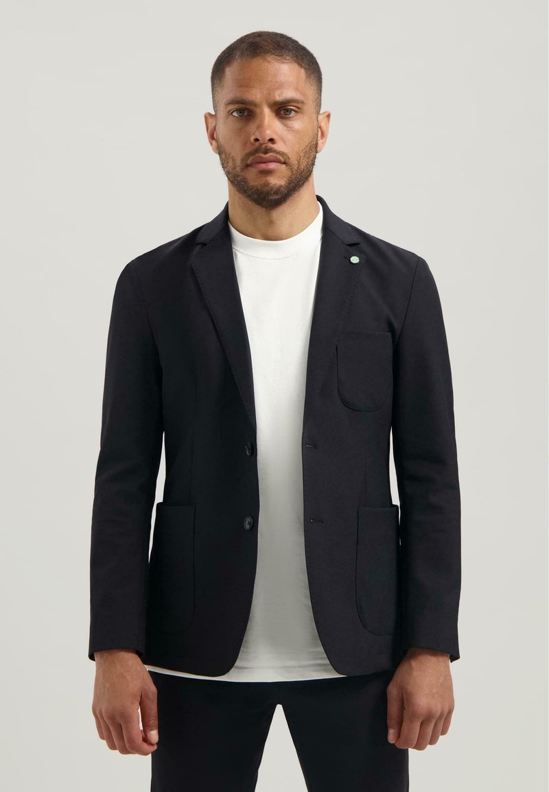 Blazer negru din material, cu rever în formă de notch, două buzunare frontale și închidere cu un singur buton. Purtați peste un tricou alb.