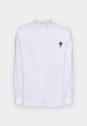 Biela košeľa s dlhými rukávmi, obsahujúca náprsné vrecko a vyšívané logo v červenej a čiernej farbe na vrecku. Bavlnená látka.