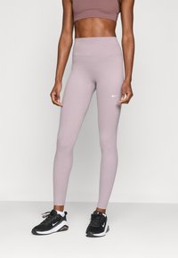 Leggings de sport taille haute de couleur violet clair, fabriqués en matériau extensible, avec un petit logo Nike blanc sur la cuisse gauche.