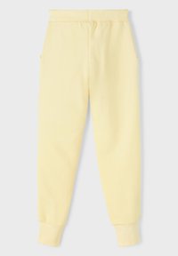 Pantalones de chándal de algodón amarillos con una cinturilla elástica, bolsillos laterales y puños acanalados en los tobillos. Textura suave y corte relajado.